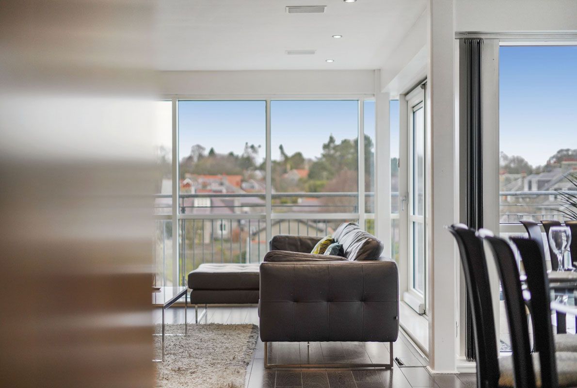 modern-looking sofa set inside a room with glass windows