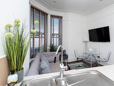 flowers beside a kitchen sink with a living room in the background