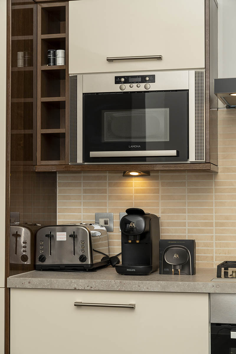 kitchen cabinet, toaster, microwave oven, and coffee maker inside Howburn Residence three-bedroom apartment