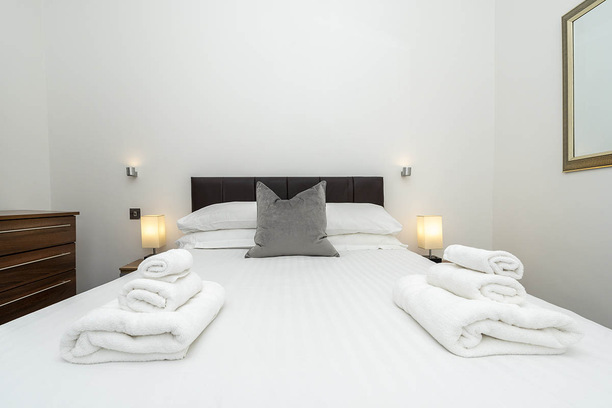 towels and pillows arranged properly on top of a bed