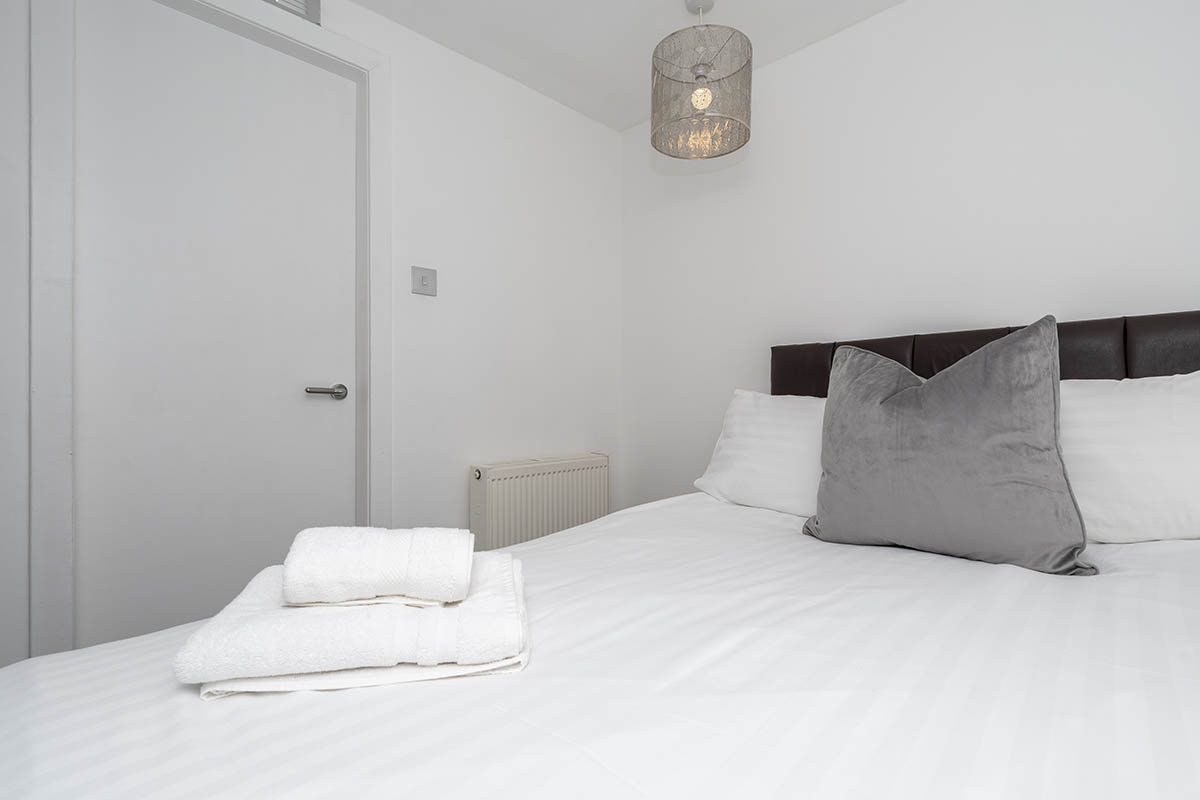 gray and white pillows on top of a bed with towels